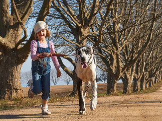 Fototapeta na wymiar Young girl running with her dog great dane. Girl and dog running