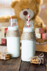 School milk bottles and oatmeal cookies on wooden background
