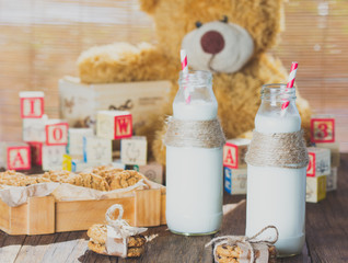 School milk bottles and oatmeal cookies on wooden background