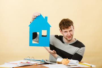 Young man with paper model of house.