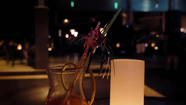 A glass filled with an alcoholic beverage cocktail on a table. People drink alcohol to loosen up and to act carefree. It definitely adds more fun in the party.