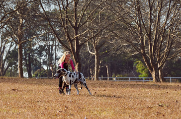 Girl and her dog running playing in  open field
