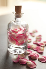 Obraz na płótnie Canvas Bottle with rose petals on grey background