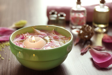 Petals in bowl with candle on wooden background