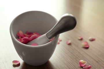 Petals in mortar on wooden background