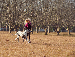 Young teen girl and her dog running playing in open field