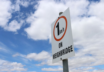 slow speed limit on weighbridge sign in blue cloudy sky