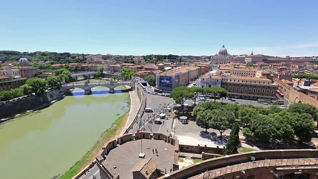 aerial view of Vittorio Emanuele II Bridge and Tevere river from overlook of Castel Sant'Angelo castle in Rome city, Italy. Saint Peter basilica on background and italian flag waving.
