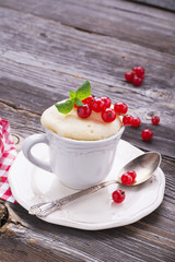 Quick breakfast snack in the microwave for a couple of minutes. Mug  semolina cake with red currants on  wooden background. selective focus