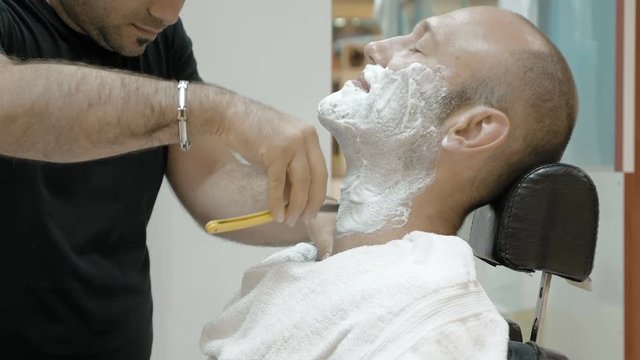 The barber is shaving his client in old fashion manner. Single blade shave gives the best result. Grooming is necessary for men and woman.