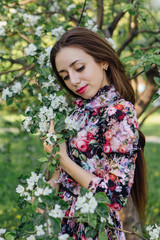 Beautiful young woman standing near the apple tree.