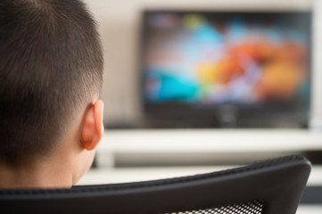 kid sitting and watching television broadcasting cartoon at home
