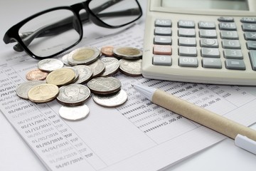 Concept of savings : Coins, glasses, calculator and pen on savings account passbook