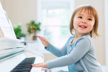 Happy smiling toddler girl playing the piano © Tierney