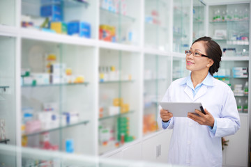 Asian pharmacist with digital tablet working in drugstore