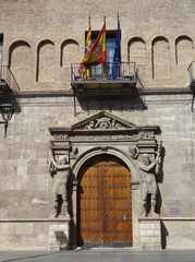 Provincial court in Saragossa. A façade with a door, two stone giants surrounding the door and a terrace with the Spain, Aragon and Europe flag