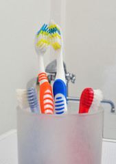 Four toothbrushes in a glass
