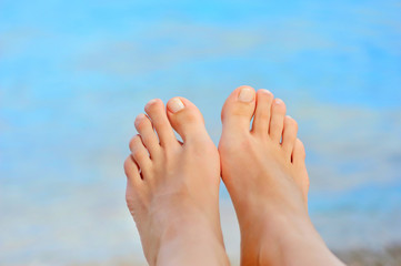 Woman feet closeup of girl relaxing on beach on sunbed