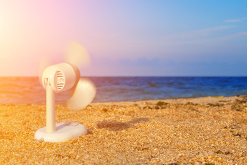 electric fan blowing on the beach in hot summer