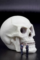 Obraz premium uomini d'affari in miniatura stringono accordo su teschio