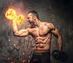 Shirtless muscular male with burning dumbbell.
