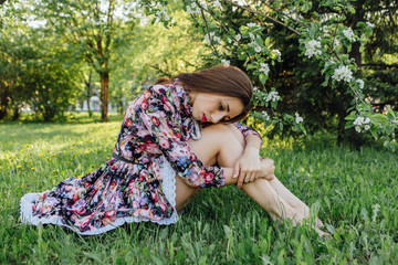 Beautiful young woman standing near the apple tree.