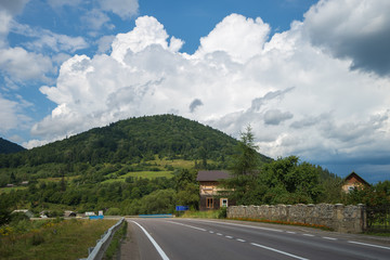 Summer day landscape with road, cloudy sky and Carpathian Mountains