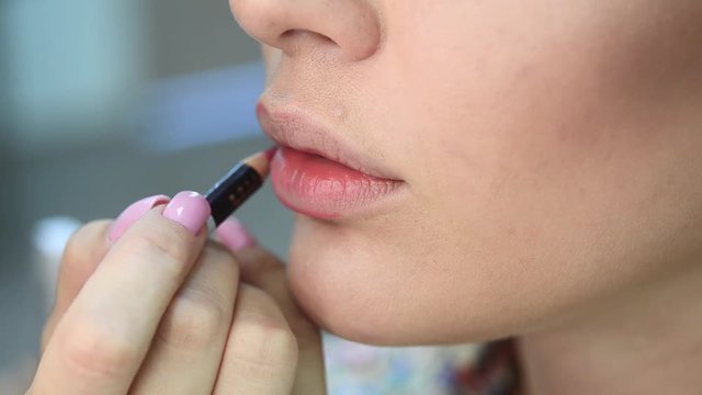 Close-up of making fashion pink lips makeup. Make-up artist apply bloody lipstick