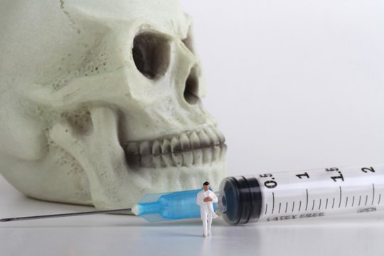 miniatura di medico con siringa e teschio