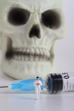 miniatura di medico con siringa e teschio