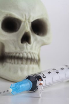 miniatura di medico con siringa e teschio