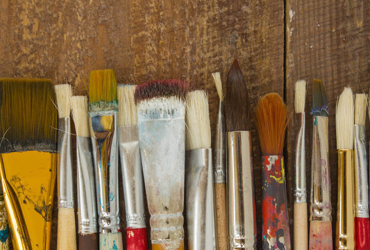 Brushes on a wooden background. The workplace of the artist. Banner for school