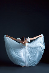 Portrait of the classical ballerina in white dress on black background