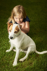 Cute little blond girl playing with her dog Jack Russell Parson Terrier.