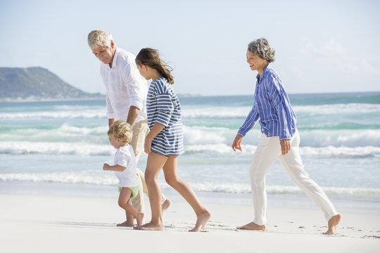 Old Couple Walking On The Beach With Their Grand Children