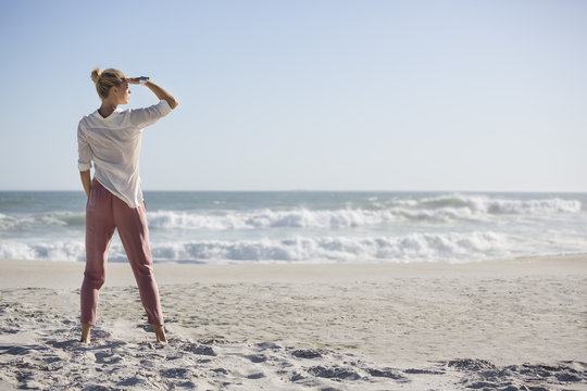 Beautiful young woman standing on sunny beach