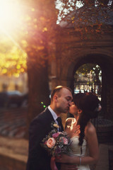 Bride and groom kiss tenderly standing in the old backyard