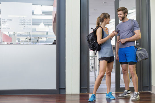 Young couple smiling at each other at the doorway of a fitness club
