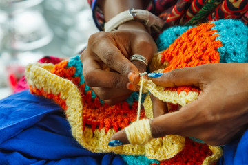 Hands of Indian woman knitting a mat