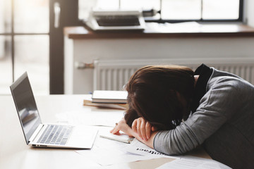 Young tired woman sleeping at office desk. Sleep deprivation, overworking, insomnia and stressful...