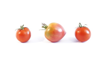Спелые помидоры  в форме сердца лежат изолированно на белом фоне