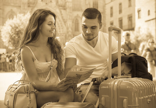 Couple with luggage reading map