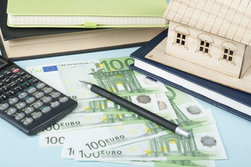 Fototapeta na wymiar Home savings, budget concept. Model house, notepad, pen, calculator and coins on wooden office desk table.