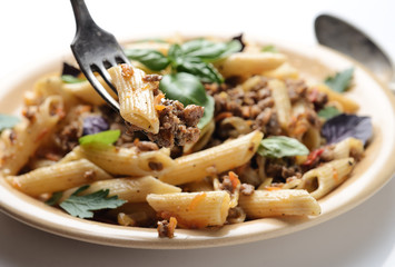 pasta with meat and basil on a plate on a white background
