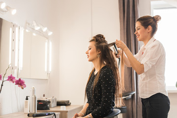 Woman at hairdresser with iron hair curler.