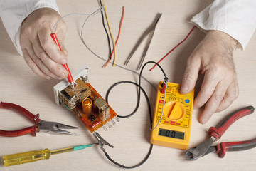 Hand of electrician with multimeter probe at  electrical switchgear cabinet. Engineering tools