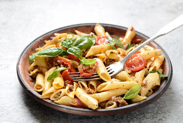 pasta with meat and basil on a plate on a gray background