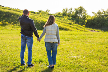 rear view of couple holding hands walking in autumn countryside