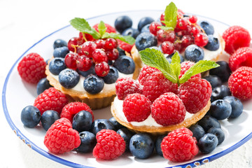 mini cakes with sweet cream and fresh berries on plate, closeup