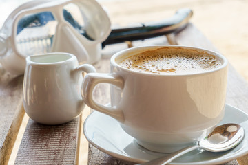 white cup of delicious coffe with foam and milk on the beach after snorkeling